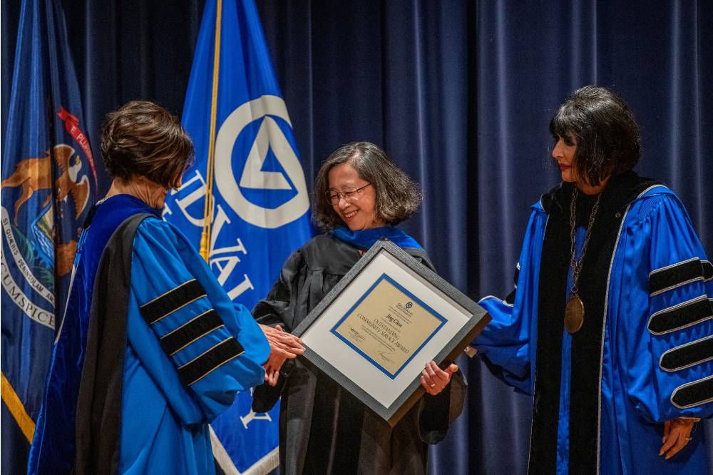 Provost Mili shakes hands with woman after receiving award